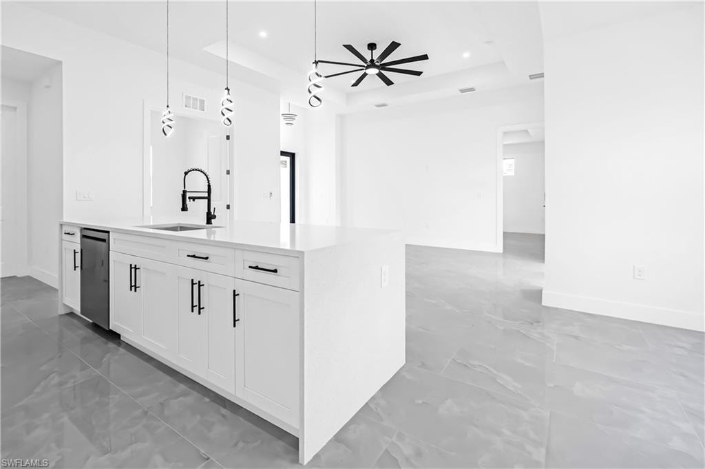 Contemporary kitchen island featuring white cabinetry, quartz-finish countertop, undermount sink with matte black faucet, and integrated dishwasher