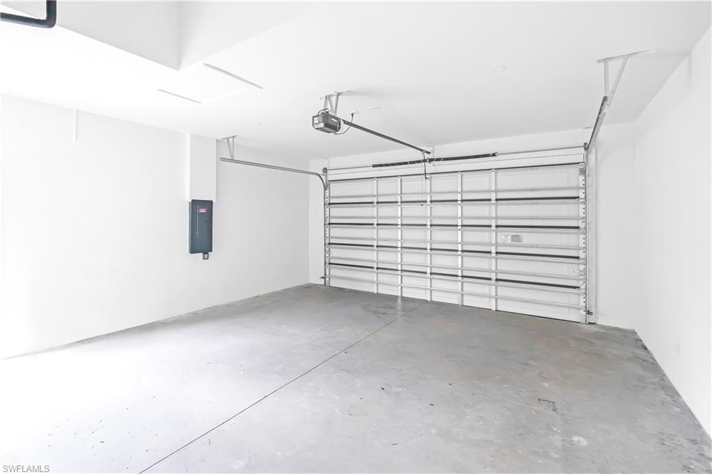 Spacious garage featuring a concrete floor, white walls, and an overhead door opener mechanism
