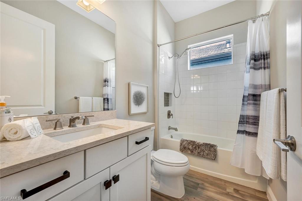 Full bathroom with hardwood / wood-style floors, vanity, toilet, and shower / tub combo with curtain