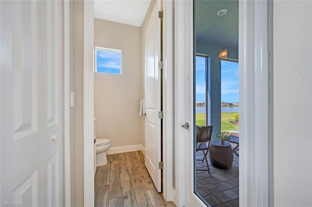 Bathroom with a water view, a healthy amount of sunlight, hardwood / wood-style floors, and toilet