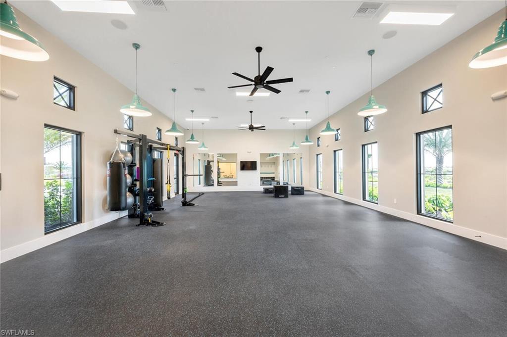 Workout area with ceiling fan, a healthy amount of sunlight, a towering ceiling, and a skylight