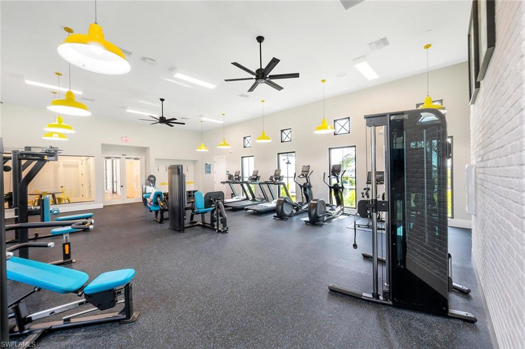 Exercise room featuring ceiling fan and a towering ceiling