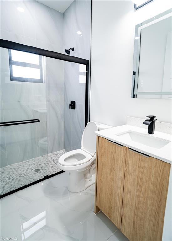 Sleek bathroom featuring a glass-enclosed shower with black fixtures and a pebble-tiled floor