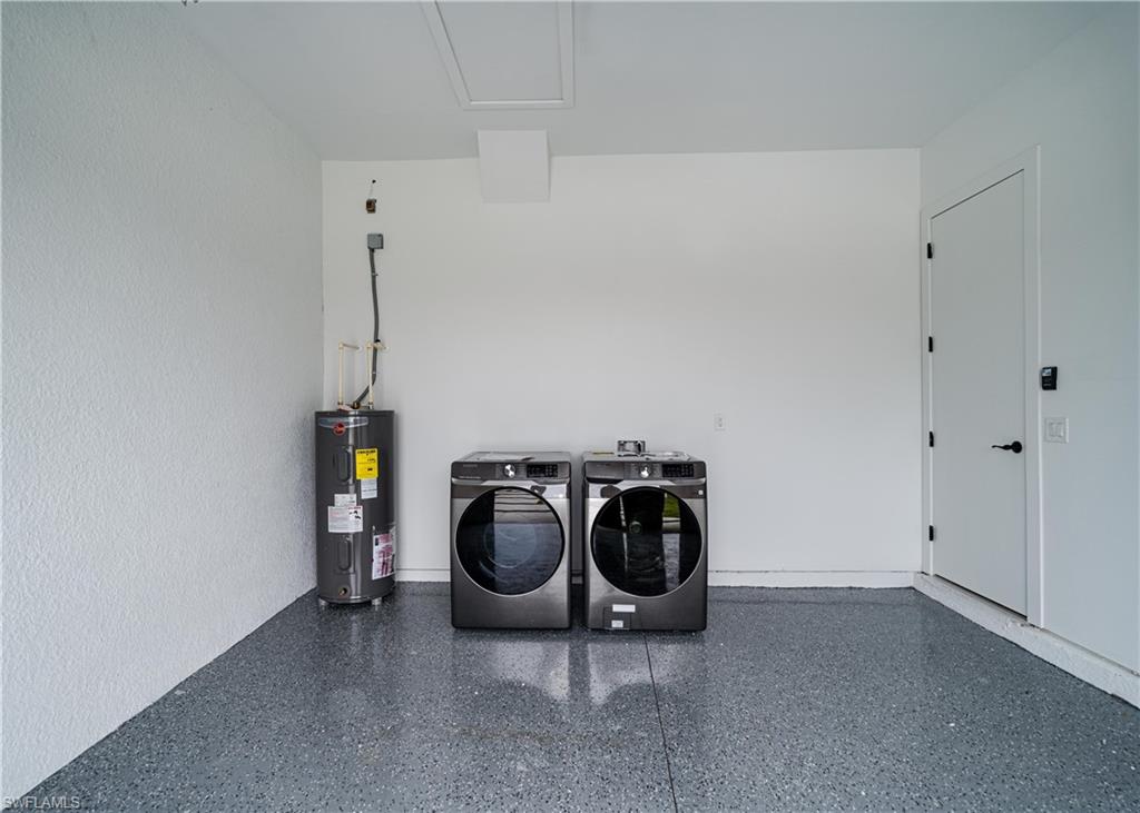 Utility area featuring a water heater, laundry appliances, and a durable epoxy-coated concrete floor