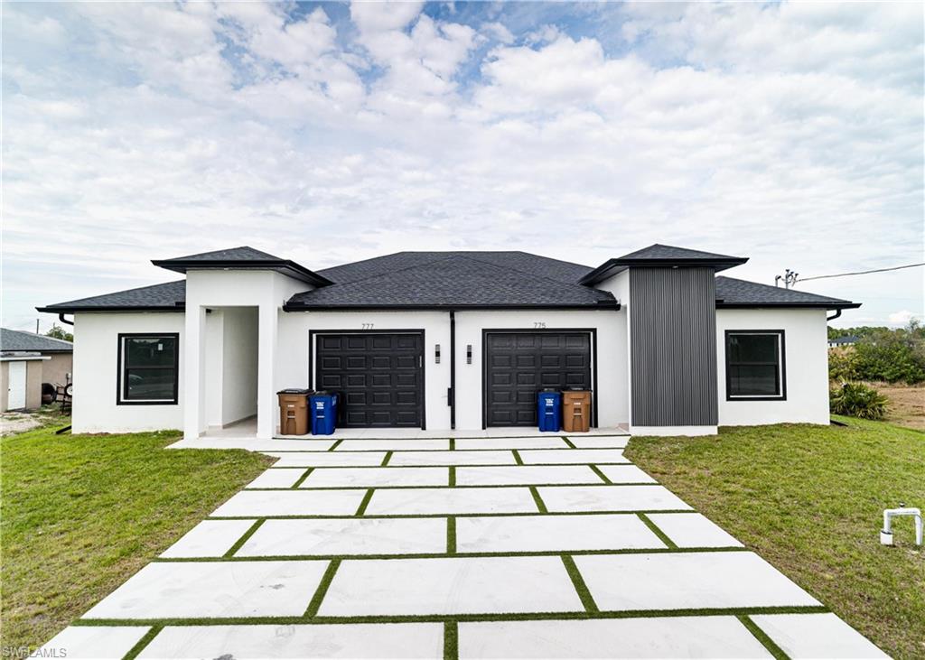 Modern duplex exterior featuring a white stucco finish and a dark shingle roof