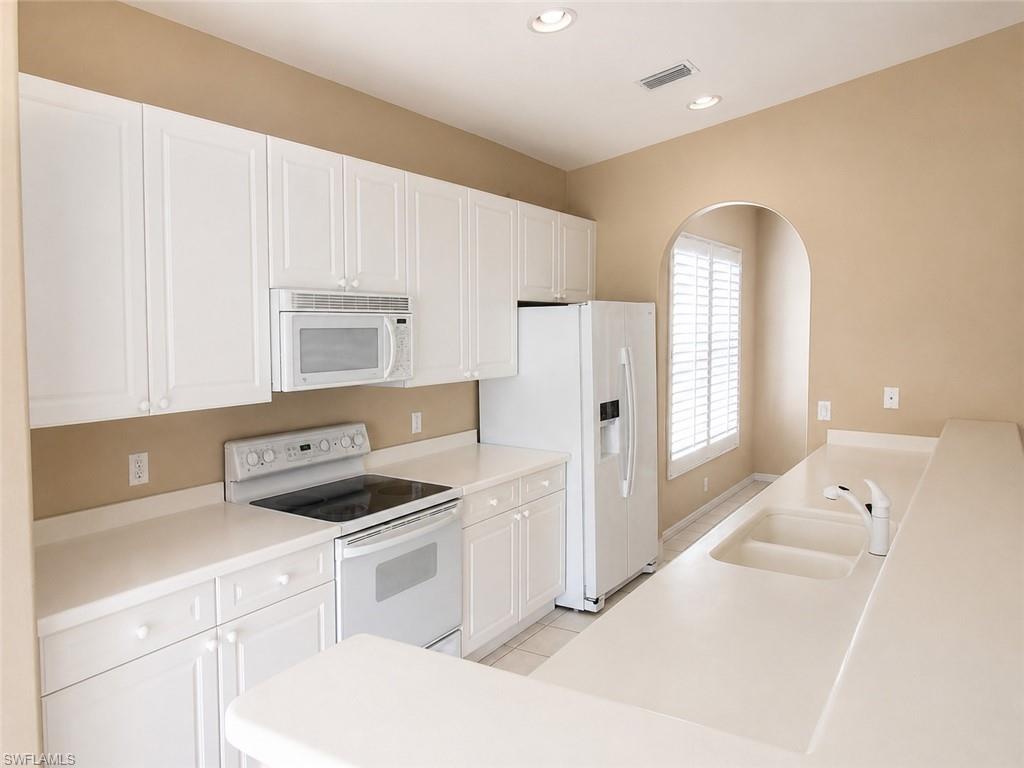 Kitchen featuring white cabinetry with shaker-style doors, white countertops, recessed lighting, and a double-basin sink with a white faucet