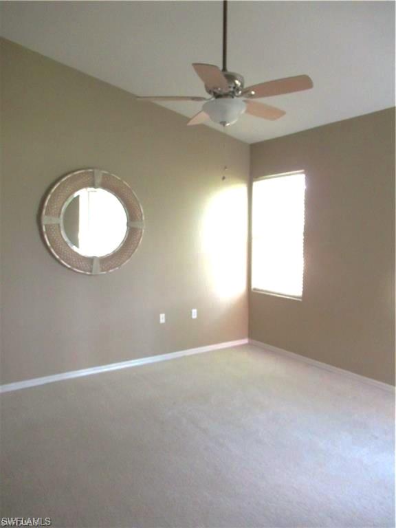 Carpeted interior space featuring a vaulted ceiling and a ceiling fan with light fixture.