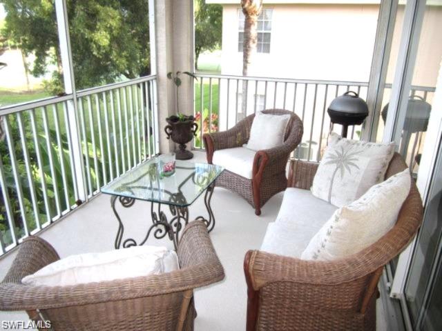 Screened outdoor living area with a white railing, tile flooring.