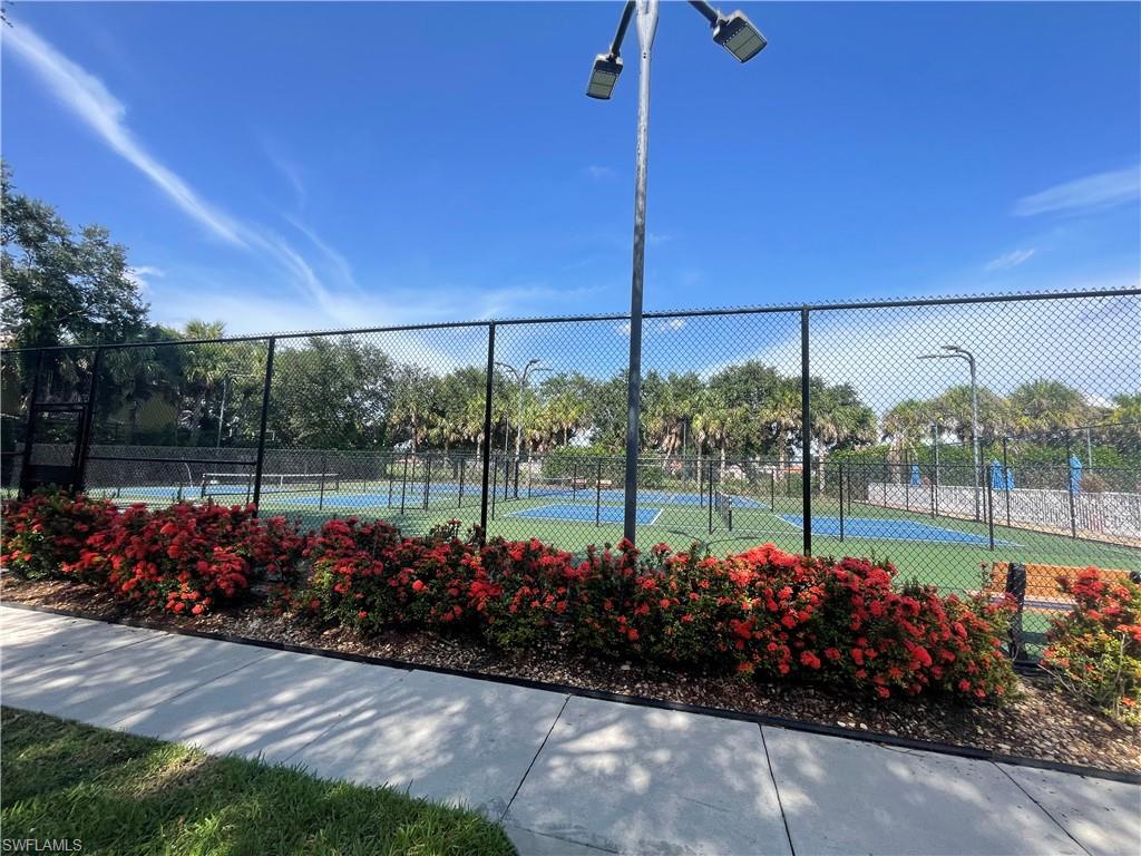 Tennis courts and basketball court featuring blue and green hard surfaces, surrounded by black chain-link fencing.