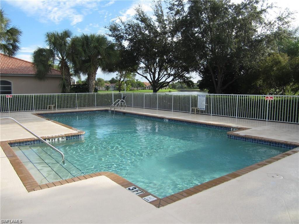Fenced swimming pool with integrated steps, concrete deck, and perimeter brick coping