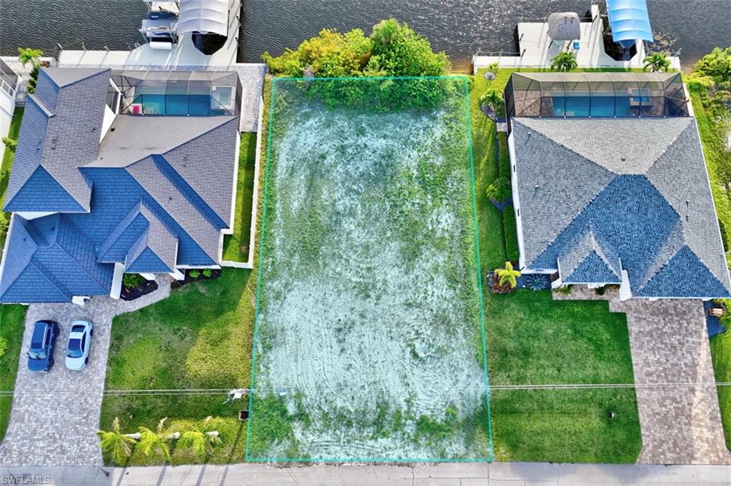 Expansive lot with canal frontage, featuring a cleared building envelope and mature landscaping