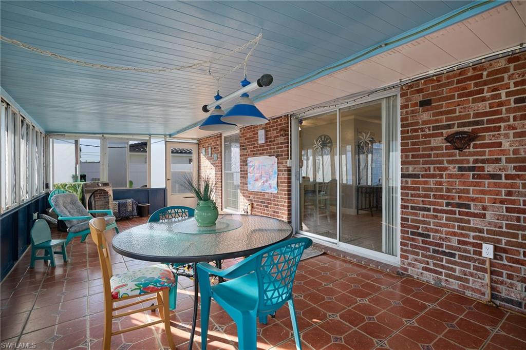 Enclosed patio featuring red brick walls, patterned tile flooring, a light blue paneled ceiling, and glass sliding doors