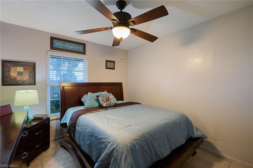 Bedroom featuring a ceiling fan with integrated lighting, window with blinds, and tile flooring