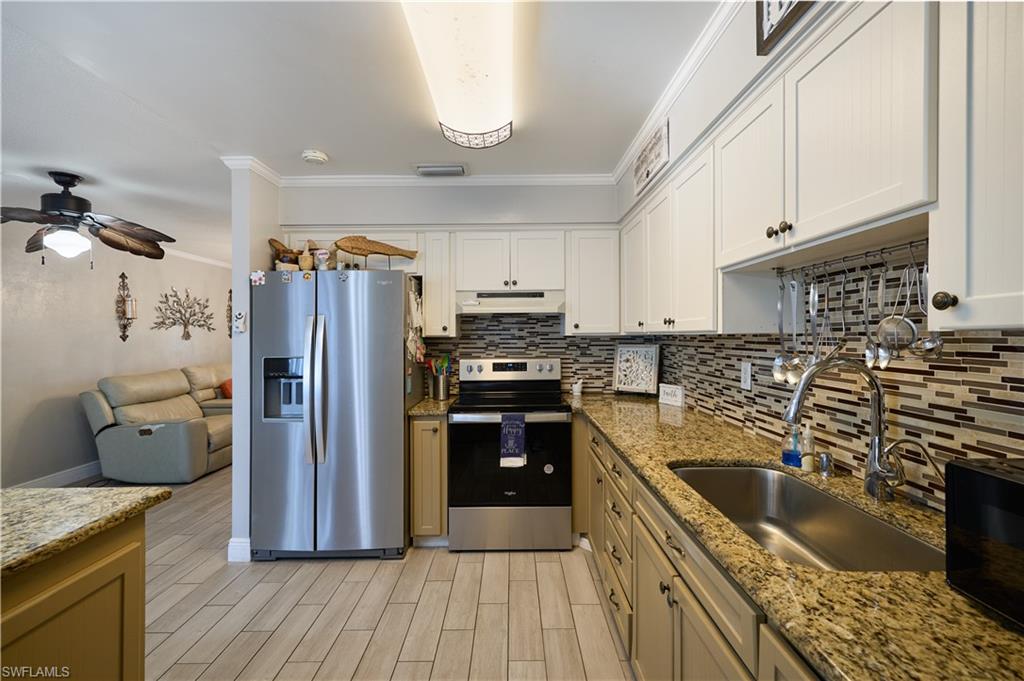 Kitchen featuring light-toned cabinetry, a multi-tone mosaic tile backsplash, and speckled countertops