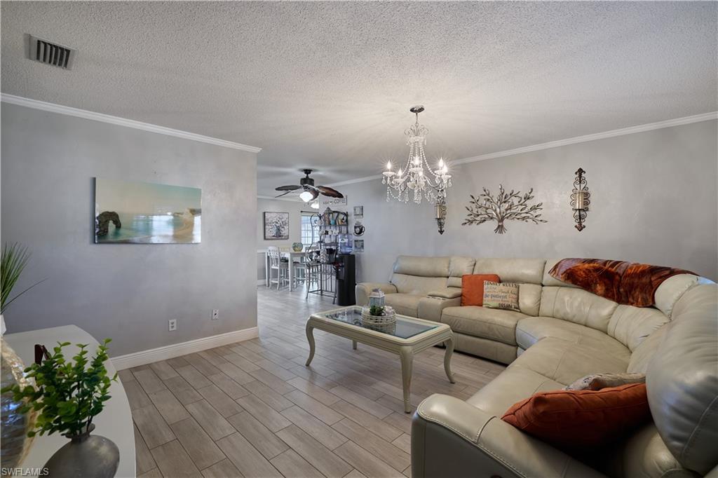 Living space featuring wood-finish flooring, crown molding, and a chandelier light fixture