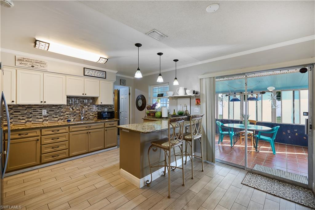 Kitchen featuring two-tone cabinetry with upper white and lower tan finishes, a mosaic tile backsplash, and granite-look countertops