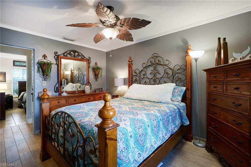 Bedroom featuring wood-finish flooring, a ceiling fan with integrated lighting, and crown molding
