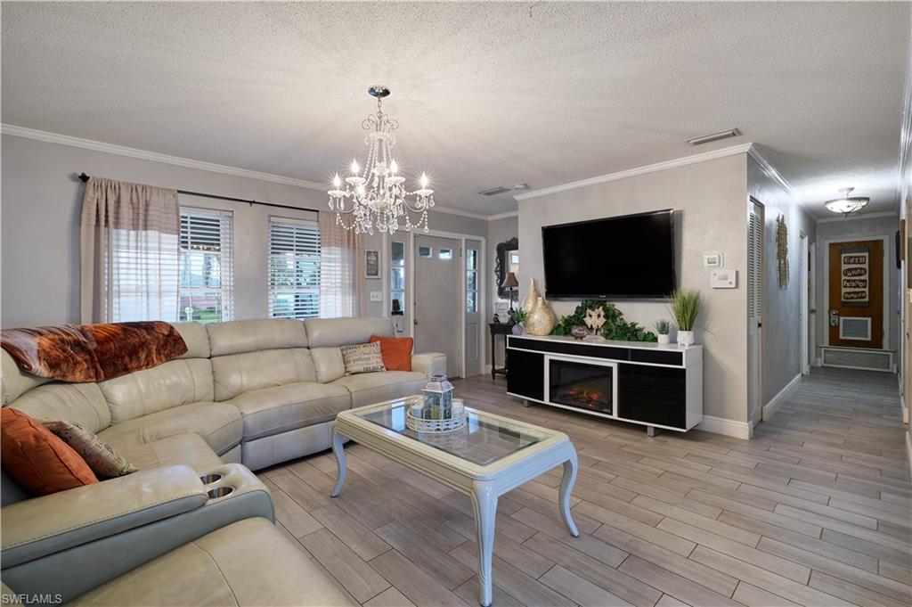 Living area featuring wood-finish tile flooring, a crystal chandelier, crown molding, and recessed lighting