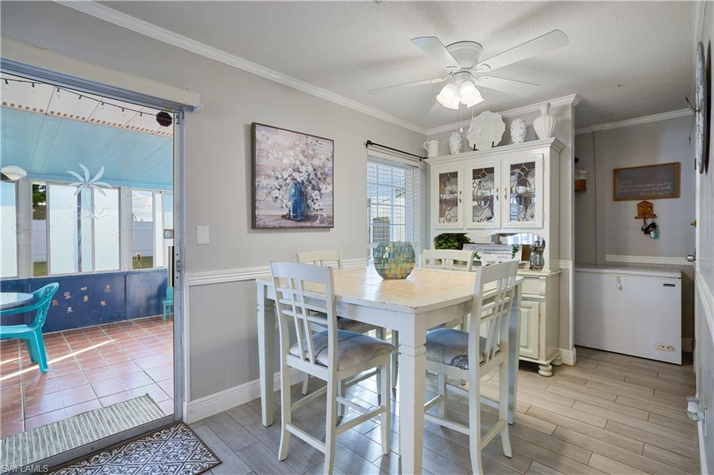 Dining area with light wood-finish flooring, a ceiling fan with integrated lighting, and chair rail molding