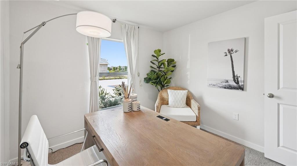 Model Home. This room features a window with white curtains, a light wood-toned desk, and white walls