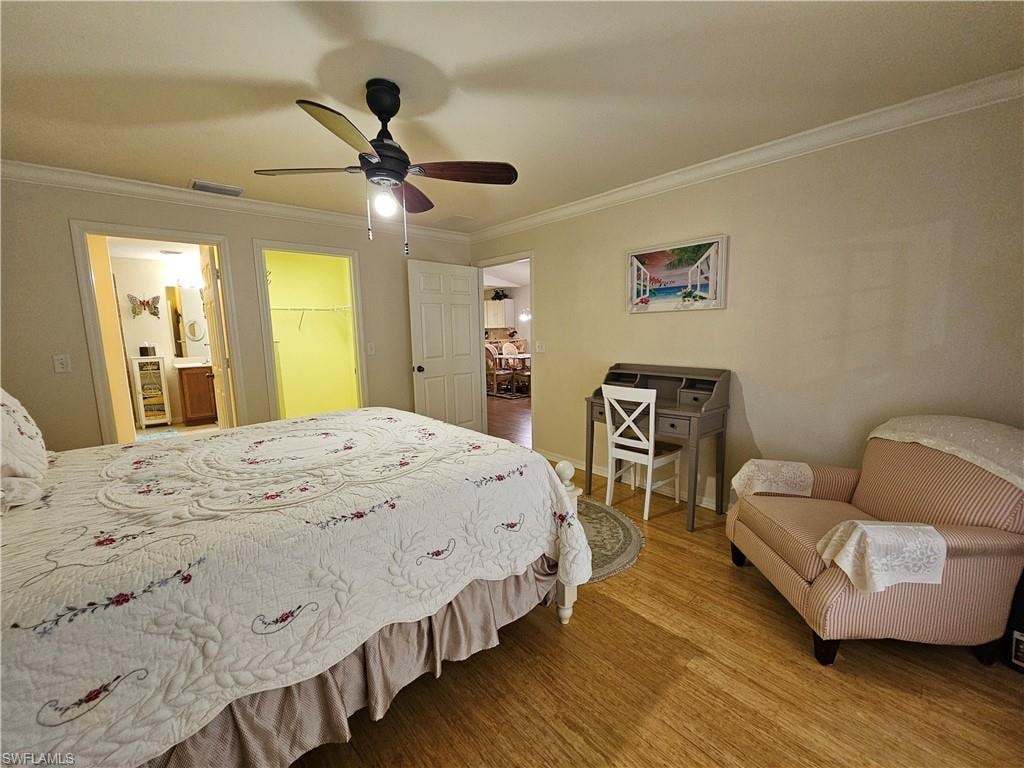 Wood-finish flooring throughout, featuring a ceiling fan with integrated lighting, crown molding, and two interior doorways