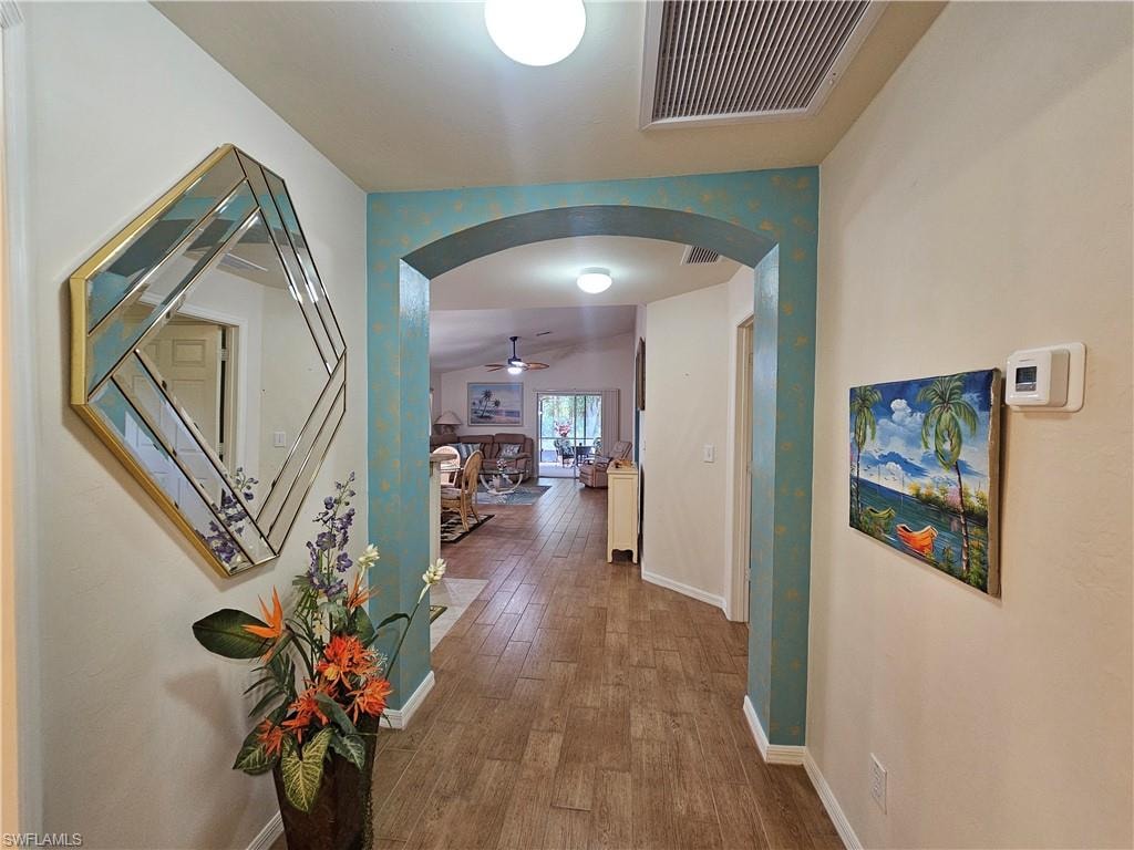 Hallway featuring wood-look tile flooring, an arched doorway, and recessed ceiling lighting