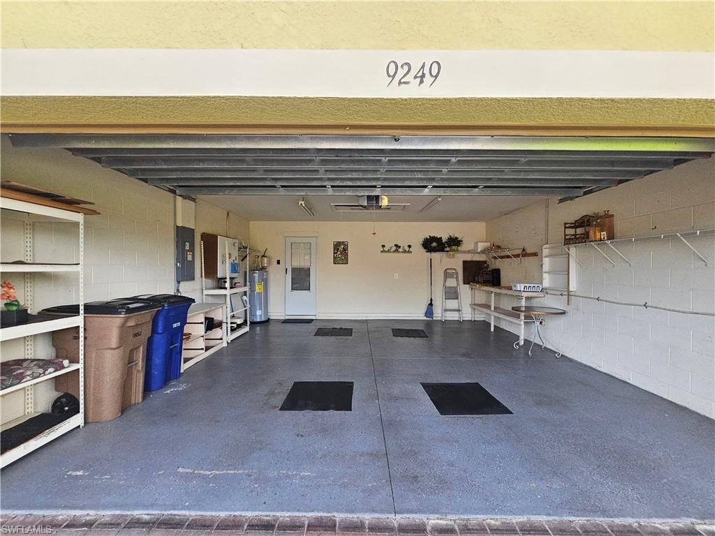 Spacious garage featuring an epoxy-coated concrete floor, an overhead garage door, interior access door, utility sink, and wall-mounted shelving