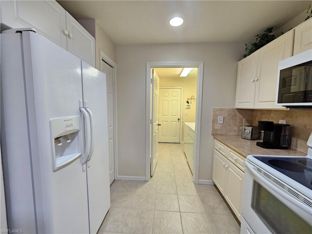 Kitchen featuring a side-by-side refrigerator, overhead microwave, and white cabinetry