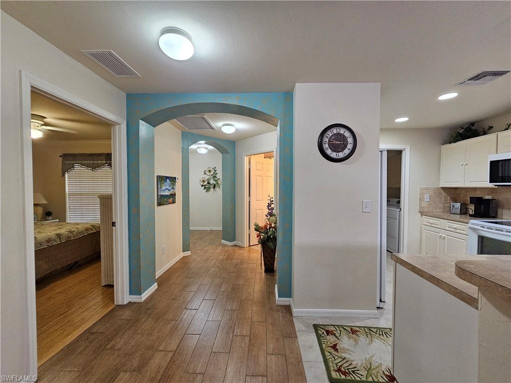 Hallway featuring wood-finish flooring, arched doorways, and recessed lighting