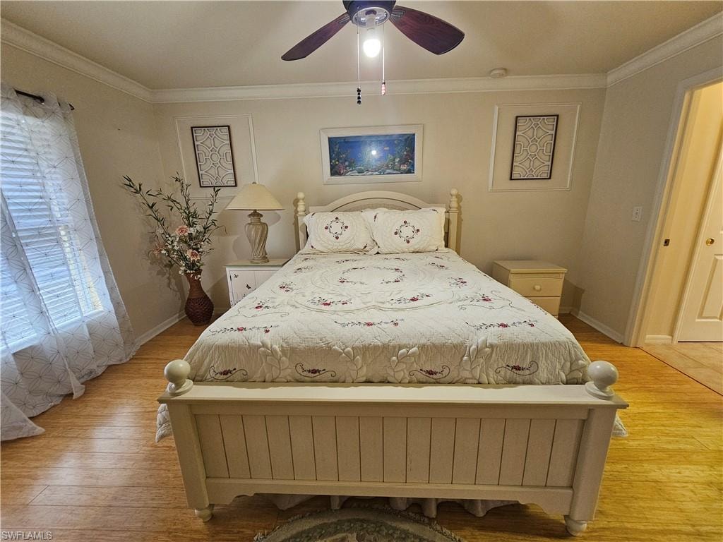 Bedroom featuring wood-finish flooring, a ceiling fan with light fixture, crown molding, and a window with horizontal blinds
