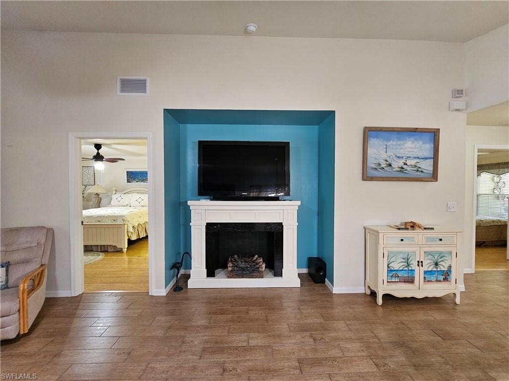 Living area featuring wood-finish flooring, a white fireplace surround with a teal accent wall, and recessed lighting