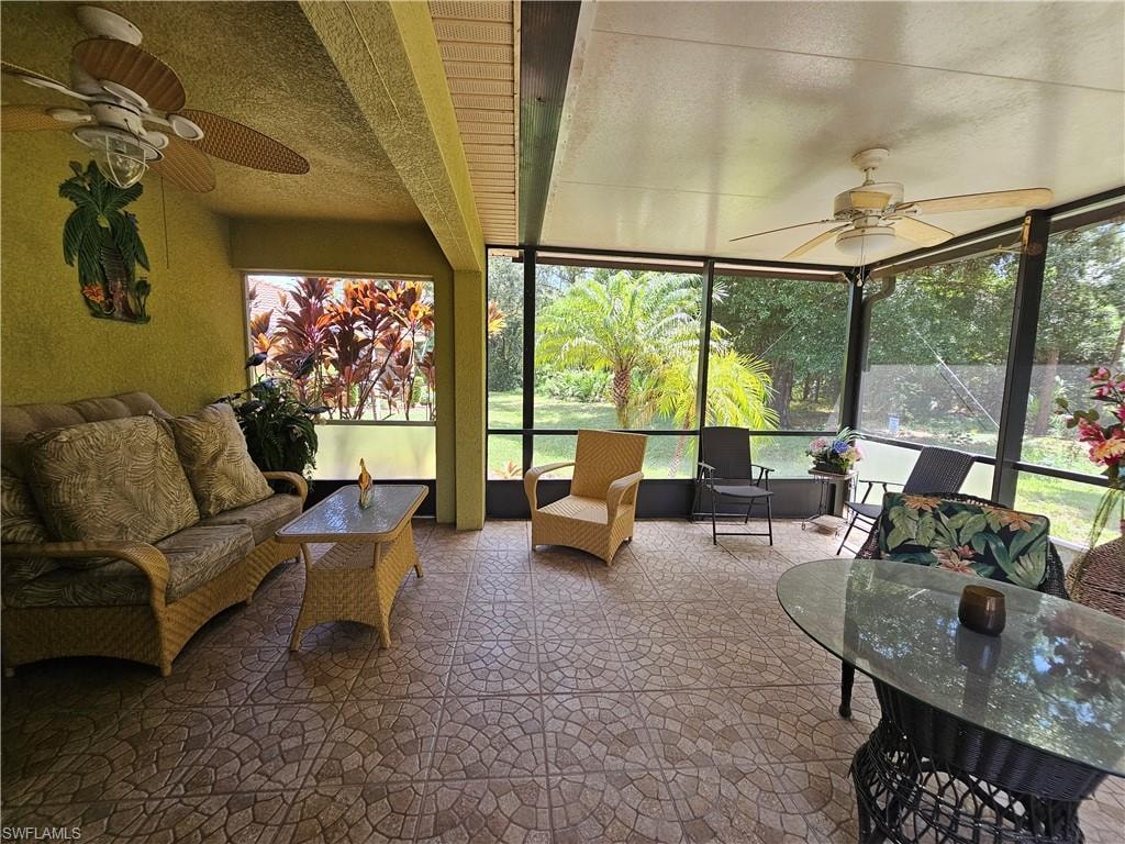 Screened porch featuring patterned tile flooring and ceiling fans