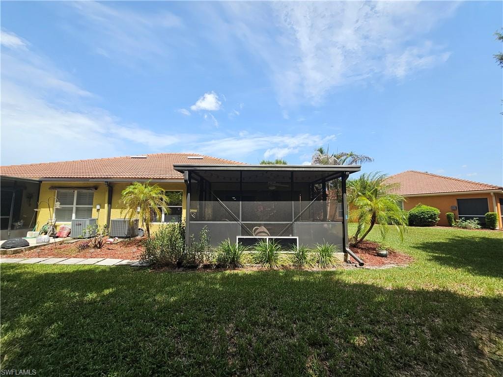 Expansive green lawn with a screened patio enclosure, mature palm trees, a terracotta-tiled roof, and a perimeter of landscaping