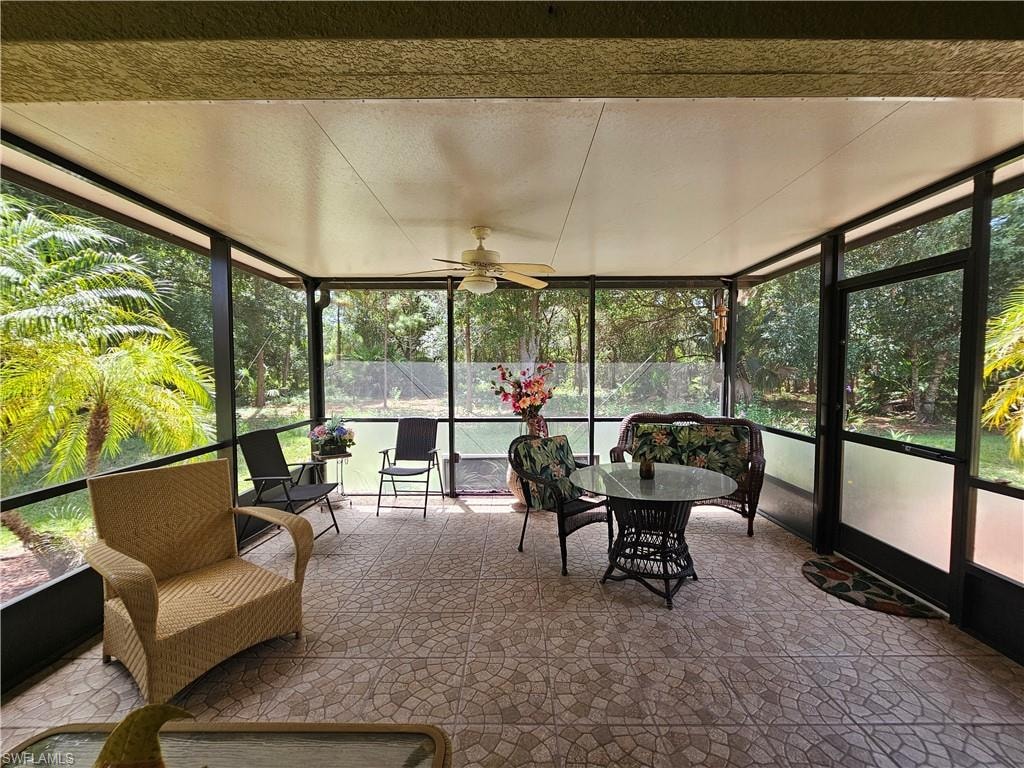 Screened lanai featuring a ceiling fan, patterned tile flooring, and a screened door