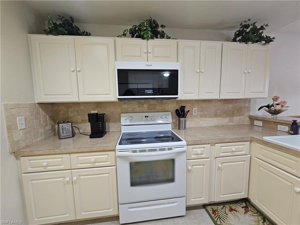 Kitchen featuring cream cabinetry, a tile backsplash, and light-toned countertops