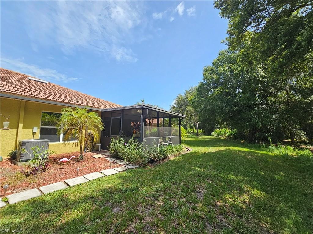 Spacious rear yard with a screened patio, expansive lawn, mature trees, and a terracotta tile roof