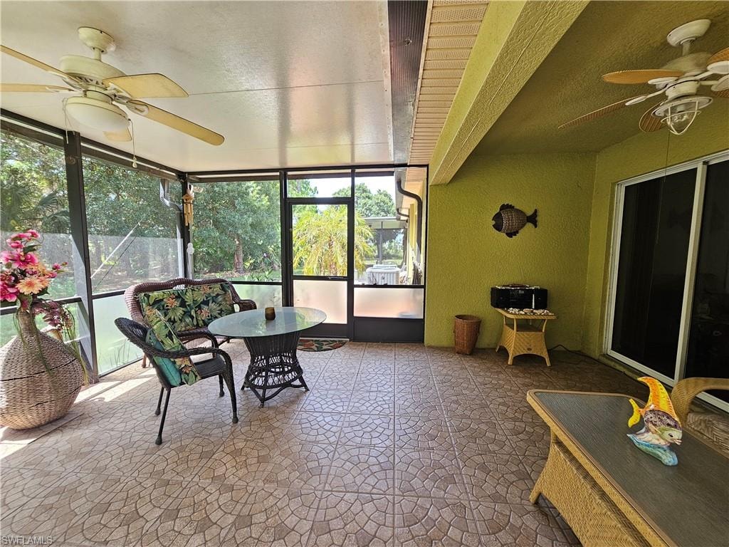 Screened patio with patterned tile flooring, exterior sliding glass doors, and dual ceiling fans