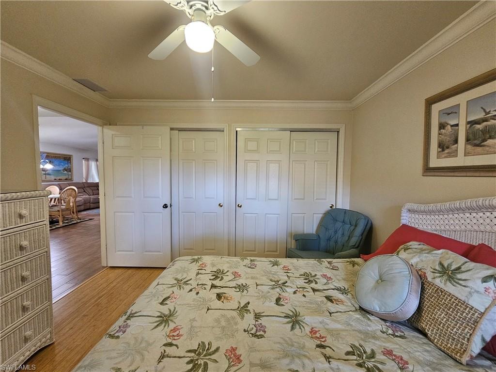 Sleeping area featuring crown molding, a ceiling fan with integrated lighting, and wood-finish flooring