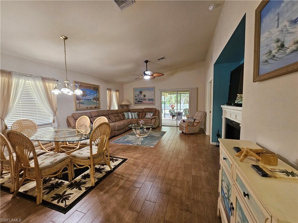 Open-concept living area featuring wood-finish flooring, vaulted ceilings, and sliding glass doors to the exterior
