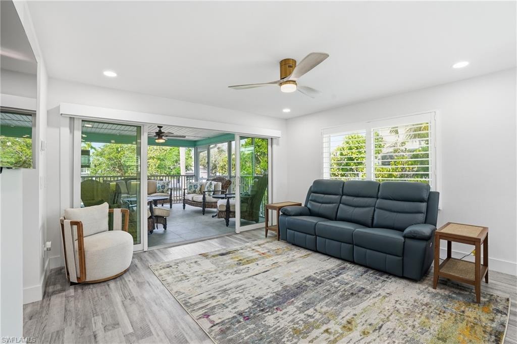 Living area featuring a ceiling fan, wood finished floors, a sunroom, and recessed lighting - Virtually Edited Image