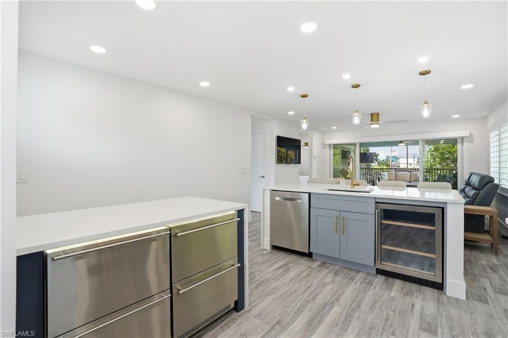 Kitchen with wine cooler, open floor plan, hanging light fixtures, recessed lighting, and light stone counters - Virtually Edited Image