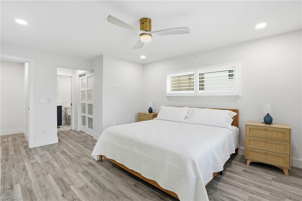 Bedroom featuring ceiling fan, connected bathroom, light wood-style flooring, and recessed lighting - Virtually Edited Image