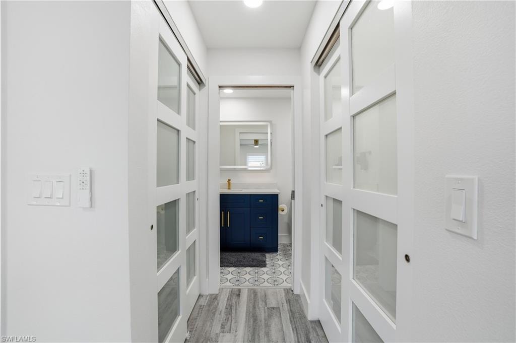 Corridor with light wood-style flooring and a sink - Virtually Edited Image