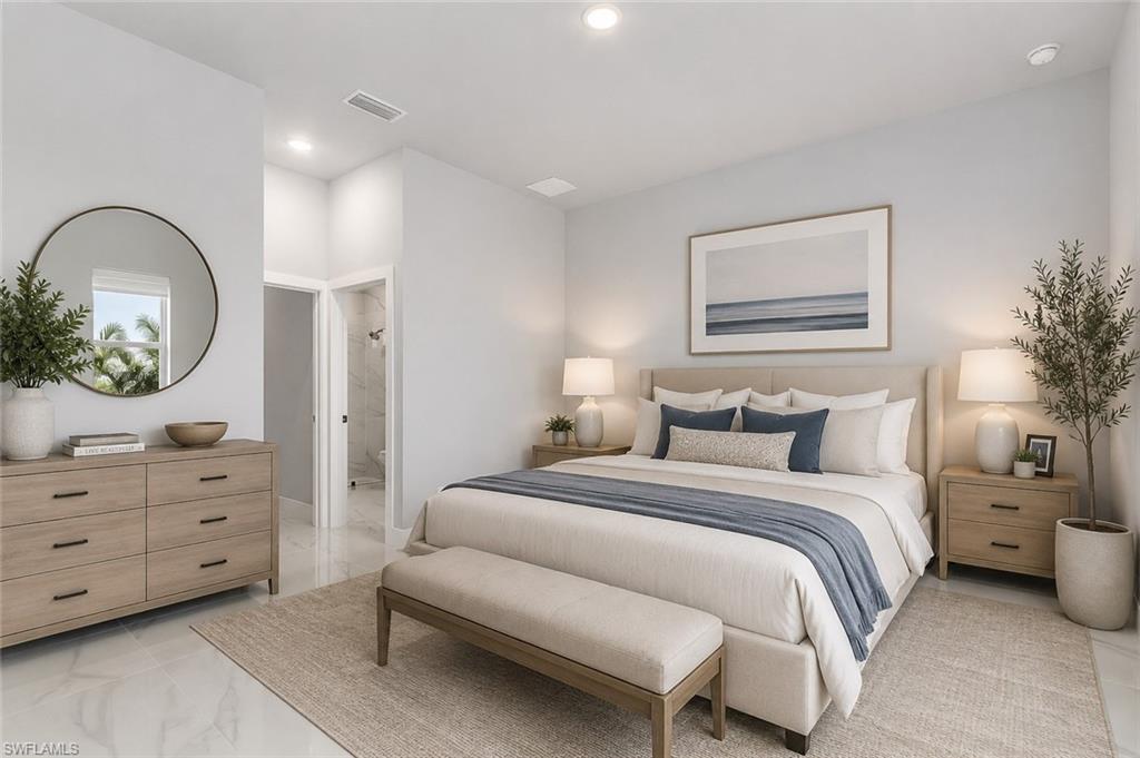 Spacious bedroom featuring light-toned walls, recessed lighting, and a doorway revealing a tiled bathroom