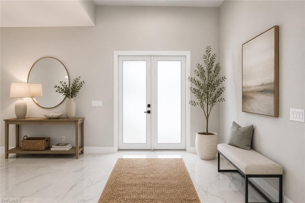 Grand entry with dual frosted glass panel doors, high ceilings, bright white walls, white tile flooring, and matching baseboards