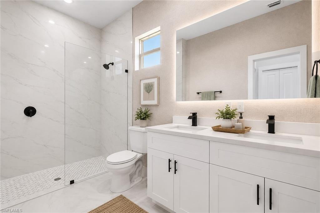 Bathroom featuring a dual vanity with white cabinetry and integrated sinks