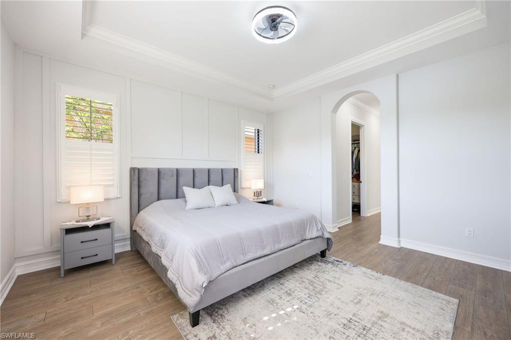 Room featuring wood-finish flooring, crown molding, and a tray ceiling