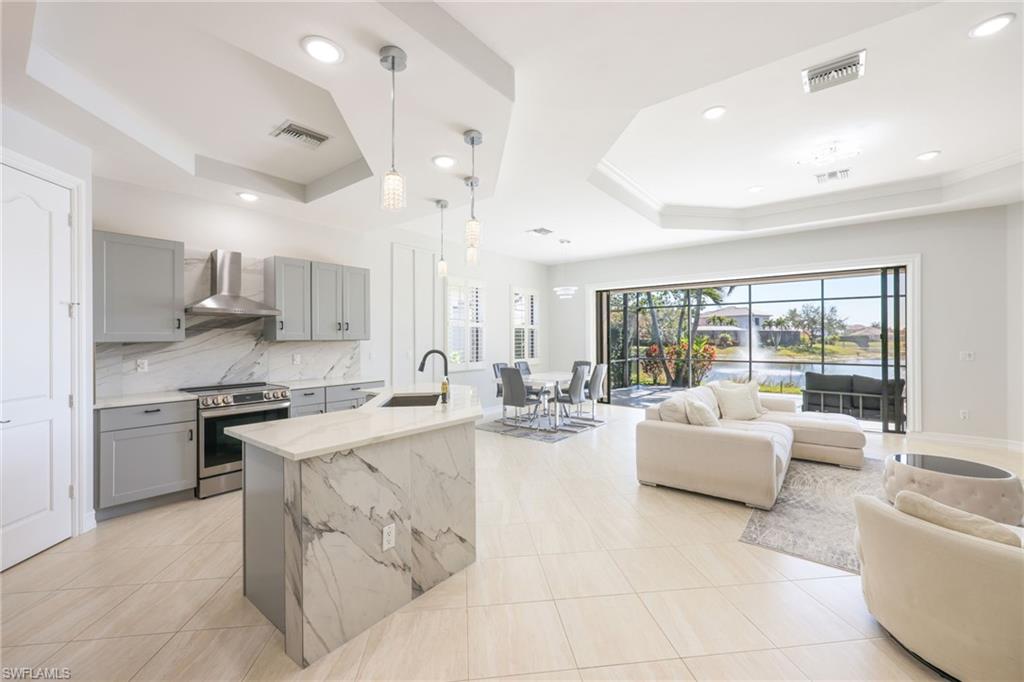 Open-concept living area featuring large format tile flooring and a tray ceiling