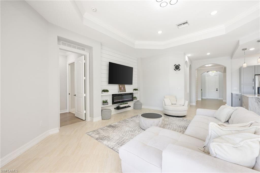 Living area featuring light wood-finish flooring, a tray ceiling, and recessed lighting