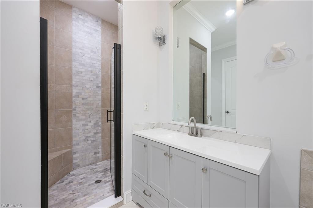 Bathroom vanity featuring a light gray cabinet with brushed nickel hardware, a white countertop, and a rectangular mirror